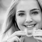 Une patiente en orthodontie tenant un appareil envisalign.