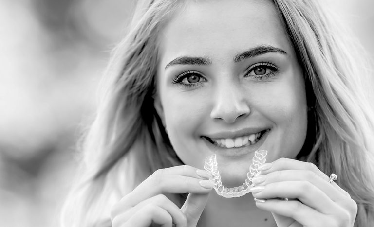 Une patiente en orthodontie tenant un appareil envisalign.