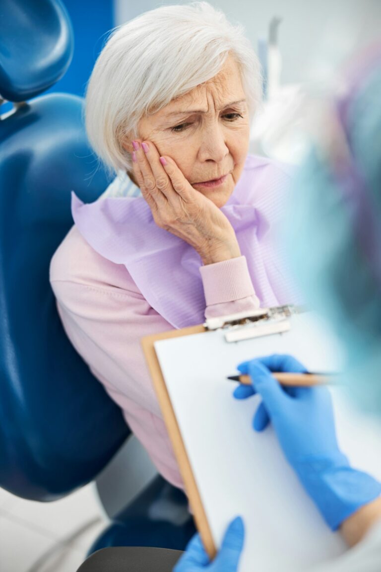 A woman holding her jaw from the pain caused by a sensitive tooth.